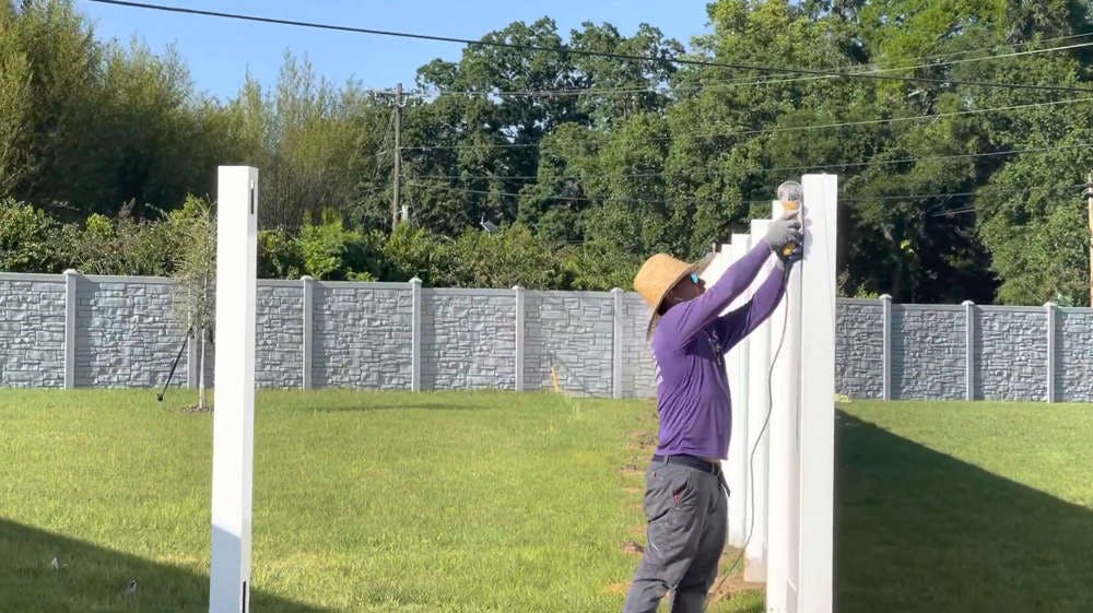 Man repairing white fence.