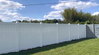 A white fence in a backyard with grass.