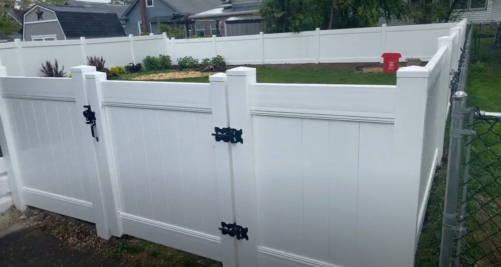 New white vinyl fence with a gate to backyard.