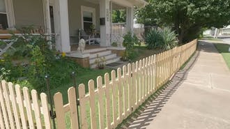 A wooden picket fence in front of a house.
